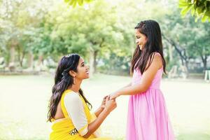 carino indiano poco ragazza e sua madre Tenere mani e parlando nel il parco foto