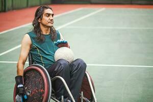 grave bello Disabilitato Rugby giocatore nel un' sedia a rotelle praticante su un' stadio foto