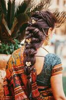 indietro lato ritratto di indiano donna indossare saree e bellissimo intrecciato pettinatura su sua lungo capelli foto