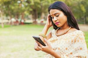 triste indiano donna indossare saree Tenere sua Telefono e avendo un' problema foto