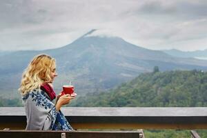 donna potabile caffè con il Visualizza di batur vulcano nel Kintamani, Bali, Indonesia foto