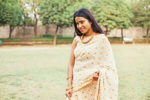 bellissimo indiano giovane donna nel elegante saree a piedi nel il parco foto