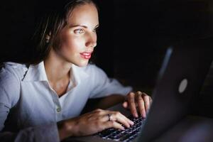 donna utilizzando computer in ritardo a notte foto
