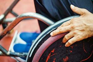 avvicinamento di un' mano su un' ruota di un' sedia a rotelle foto