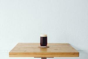 un' potabile bicchiere di freddo infuso tuffo caffè su il tavolo con bianca parete sfondo. foto