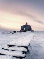 cabine nel inverno. innevato scala principale attraverso cumuli di neve per un' solitario Casa su un' cima nel il sera. foto