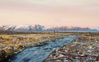 ghiacciato inverno strada attraverso il tundra colline nel teriberka. meraviglioso panoramico montagna paesaggio con tundra su il barents mare. foto