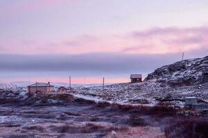 settentrionale magenta tramonto con un' Visualizza di il ospite case su il innevato polare collina. foto