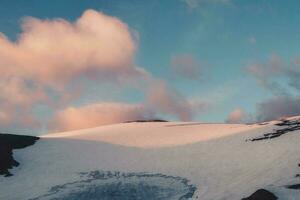 sera drammatico minimo paesaggio con illuminata dal sole alto neve montagna superiore sotto rosa nuvoloso cielo a tramonto. bellissimo alpino paesaggio con grande nevoso montagna. foto