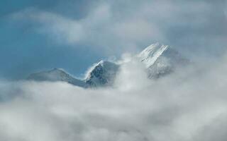 morbido messa a fuoco. meraviglioso minimalista paesaggio con grande nevoso montagna picchi sopra Basso nuvole. atmosferico minimalismo con grande neve montagna cime, buio ghiacciaio nel drammatico cielo. foto