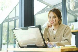 giovane femmina Università alunno usi un' computer per accesso il Internet per in linea apprendimento. foto