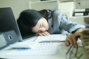 giovane asiatico attività commerciale donna stanco donna addormentato su scrivania con il computer portatile a posto di lavoro solo. foto