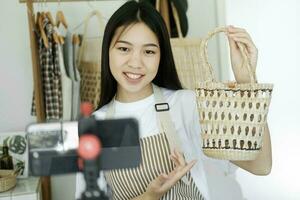 vicino su giovane asiatico donna d'affari moda blogger mostrando intrecciata cestino prodotti con sorridente. foto