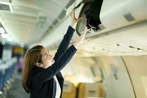 donna d'affari mettendo bagaglio su il superiore mensola su aereo. foto