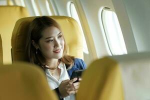 attività commerciale donna nel un' aereo, lavori su utilizzando su Telefono. foto