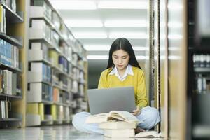 alunno seduta su il pavimento e studiando a biblioteca. foto