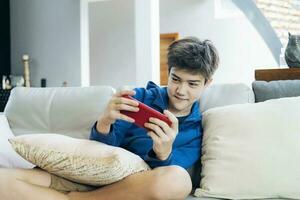 il ragazzo giocando in linea gioco su smartphone a casa foto