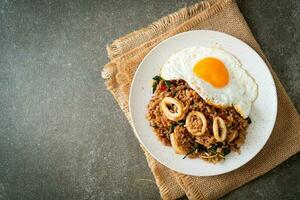 riso fritto con calamari e uovo fritto condito con basilico in stile tailandese foto