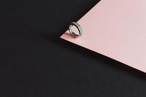un minimalista anello di diamanti girato su uno sfondo rosa e nero
