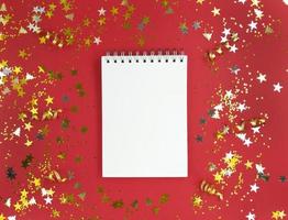 foglio bianco bianco del taccuino su uno sfondo rosso con coriandoli sparsi concetto di educazione vacanza stock foto