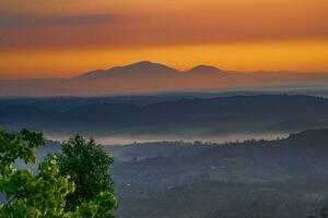 montagna gamma con visibile sagome attraverso il mattina colorato nebbia foto