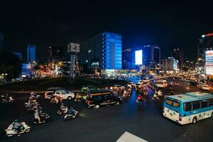 ho chi minh città, Vietnam - apr 14, 2023 traffico marmellata a morire bien phu rotatoria con suo quadrifronte orologio Torre un' simbolo di ho chi minh città. leggero pista a partire dal macchine. foto