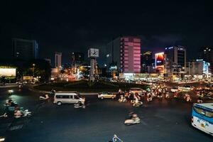 ho chi minh città, Vietnam - apr 14, 2023 traffico marmellata a morire bien phu rotatoria con suo quadrifronte orologio Torre un' simbolo di ho chi minh città. leggero pista a partire dal macchine. foto