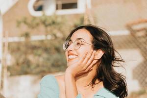 giovane donna con gli occhiali sorridendo alla telecamera durante una giornata di sole super con copia spazio lifestyle concept happy day foto