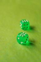 una macro monocromatica vibrante con profondità di campo circa due dadi da gioco in vetro verde con due fortunati numero sei su sfondo verde foto