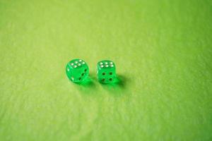 una macro monocromatica vibrante con profondità di campo circa due dadi da gioco in vetro verde con due fortunati numero sei su sfondo verde