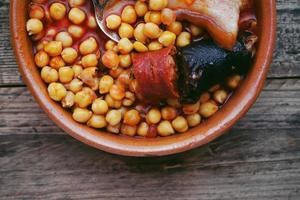 piatto di salsiccia di ceci e pancetta in una pentola di terracotta foto