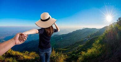 donna che tiene la mano di suo marito mentre corrono insieme sulla montagna foto