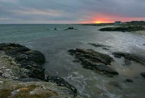 drammatico nuvoloso tramonto scenario di roccioso a selvaggio atlantico modo, alga marina spiaggia nel contea Galway, Irlanda foto