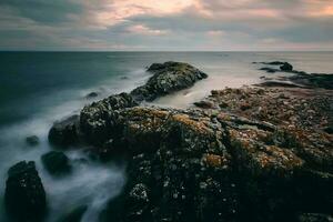 drammatico nuvoloso tramonto paesaggio marino scenario di roccioso costa a selvaggio atlantico modo, alga marina spiaggia nel contea Galway, Irlanda foto