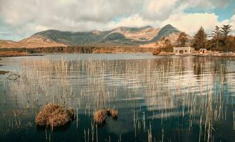 bellissimo paesaggio scenario di Casa di il lago con montagne nel il sfondo a lough inagh nel connemara nazionale parco, contea Galway, Irlanda foto