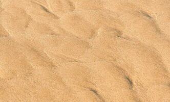 sabbia spiaggia struttura sfondo nel estate, superiore Visualizza Marrone sabbioso ruvido superficie con onda ondulazione di mare acqua con copia spazio per estate bandiera disegno, naturale sabbia pietra di il mare foto