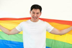 allegro giovane uomo avvolto nel arcobaleno bandiera godendo isolato su bianca sfondo. omosessuale lgbtiq concetto, arcobaleno bandiera, festeggiare parata. copia spazio. foto