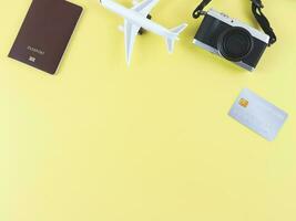 piatto posare di aereo modello, passaporto, credito carta e digitale telecamera isolato su giallo sfondo con copia spazio. viaggio pianificazione concetto. foto