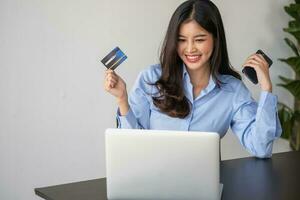 bellissimo asiatico donne utilizzando credito carte per shopping in linea con computer portatili e smartphone, in linea shopping ritratto concetto. foto