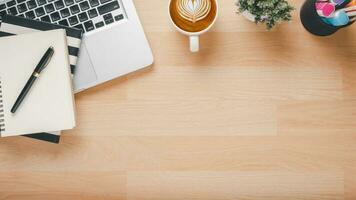 di legno scrivania posto di lavoro con computer portatile, taccuino, penna e tazza di caffè, superiore Visualizza piatto posare con copia spazio. foto