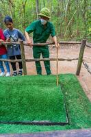 il cu chi tunnel. il personale mostrando uso il trappola nel cu chi tunnel. è Usato nel Vietnam guerra. famoso turista attrazione nel Vietnam. azione foto