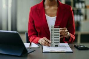 giovane vero tenuta agente lavoratore Lavorando con il computer portatile e tavoletta a tavolo nel ufficio e piccolo Casa accanto esso. foto