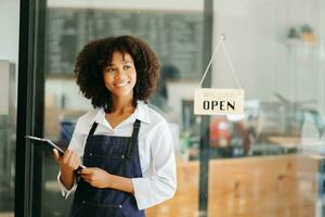 avviare riuscito piccolo attività commerciale proprietario pmi africano donna In piedi con tavoletta nel bar ristorante. donna barista bar proprietario. foto