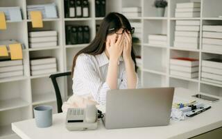 asiatico attività commerciale donna è stressato, annoiato, e troppi pensieri a partire dal Lavorando su un' tavoletta a il moderno ufficio. foto