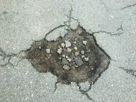il struttura di Cracked vecchio asfalto. grande buca nel nazione asfalto strada foto