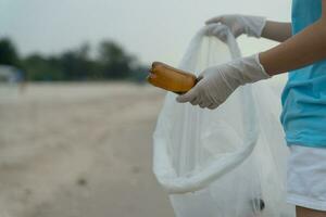 Salva acqua. volontario raccogliere su spazzatura spazzatura a il spiaggia e plastica bottiglie siamo difficile decomporsi impedire danno acquatico vita. terra, ambiente, greening pianeta, ridurre globale riscaldamento, Salva mondo foto