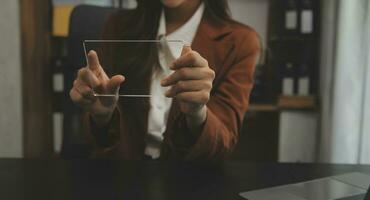 il ritratto di una giovane donna asiatica libera professionista sta lavorando sul tablet del computer in un ufficio moderno. fare un rapporto di analisi contabile dati di investimento immobiliare, concetto di sistemi finanziari e fiscali. foto