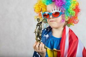 statua di themis nel il mano di cinque anni vecchio bambino vestito nel clown costume. foto