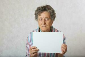 vecchio donna con un' pezzo di scatola di cartone carta foto