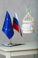 il piccolo gabbia e il parola sanzioni allegato per esso. bandiere di Unione Europea e Russia nel il sfondo foto